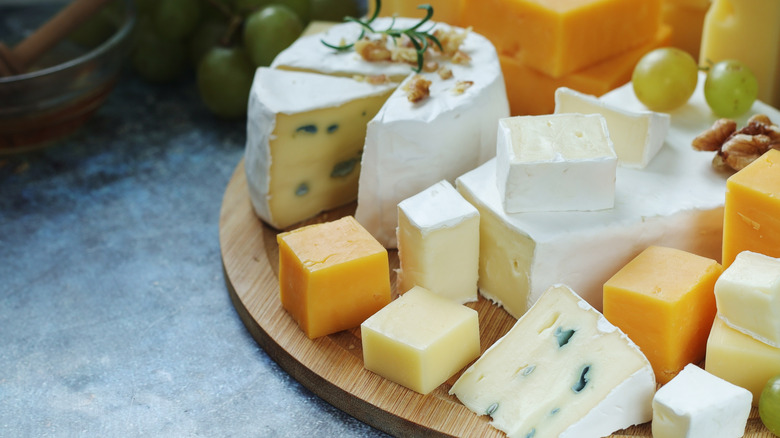 a variety of cheeses on a wooden board