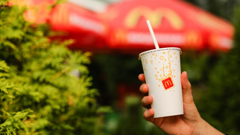 hand holding a cup of McDonald's lemonade against trees in background