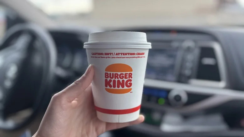 A person holding a Burger King to-go coffee in their hand.
