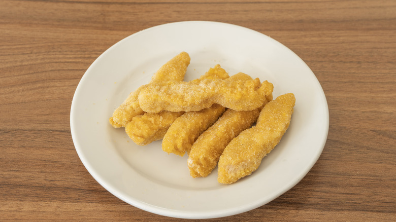 Breaded chicken tenders sit on a white plate