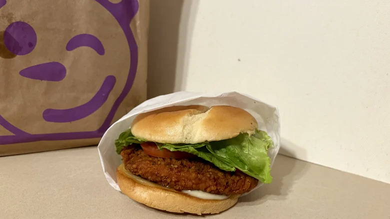 A Jack in the Box chicken sandwich in paper on a counter.