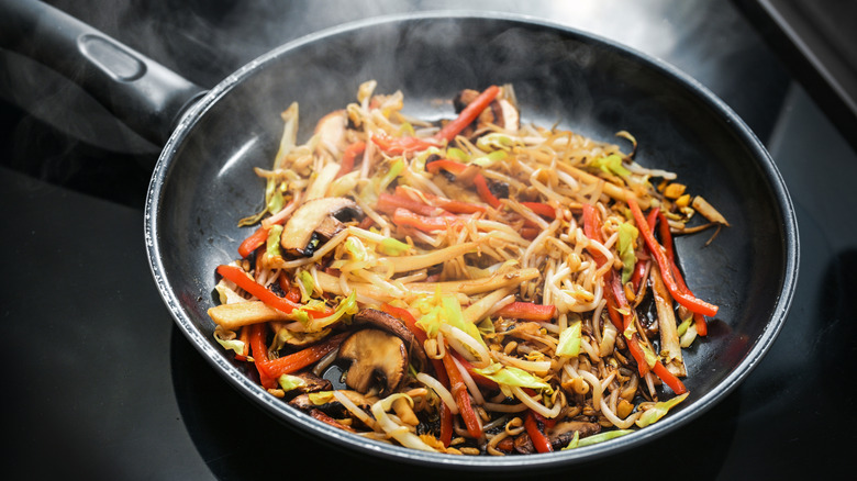 a hot pan has veggies stir-frying