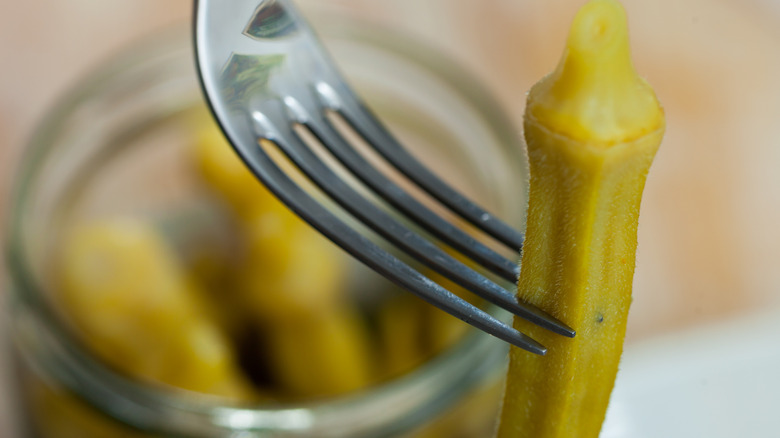 A close-up image of a fork spearing a pickled okra