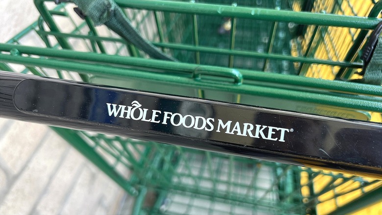 Close up of Whole Foods Market green shopping cart with black handle