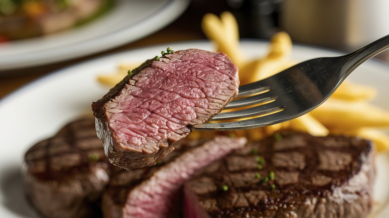 Medium-rare cooked slice of steak on a fork