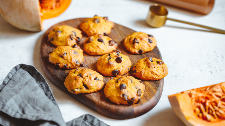 Pumpkin chocolate chip cookies on a round wooden cutting board