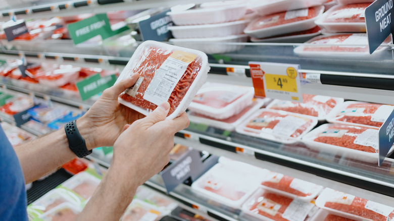 Person holding packaged meat in a grocery store