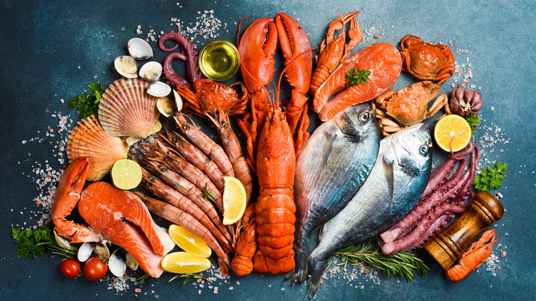 Raw seafood, including salmon filets, shrimp, lobster, octopus, and crab arranged decoratively in a half-circle
