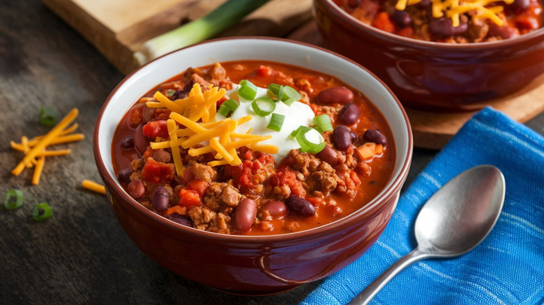 Bowl of chili with cheese, sour cream, and scallions