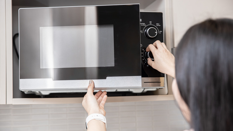 Person using a microwave oven