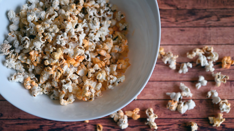 Bowl of popcorn scattered on a wooden table
