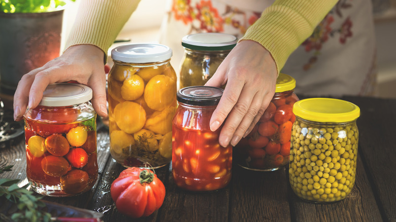 a woman's hands touching various canned vegetables
