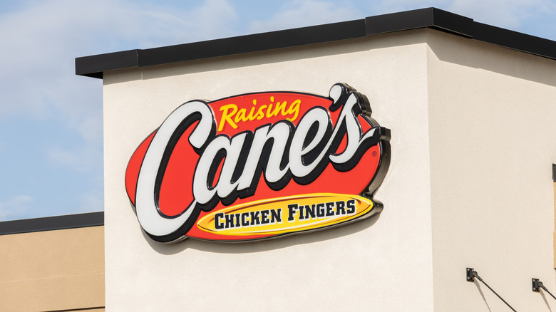 Red, white, and yellow Cane's Chicken Fingers sing on off-white stucco building exterior