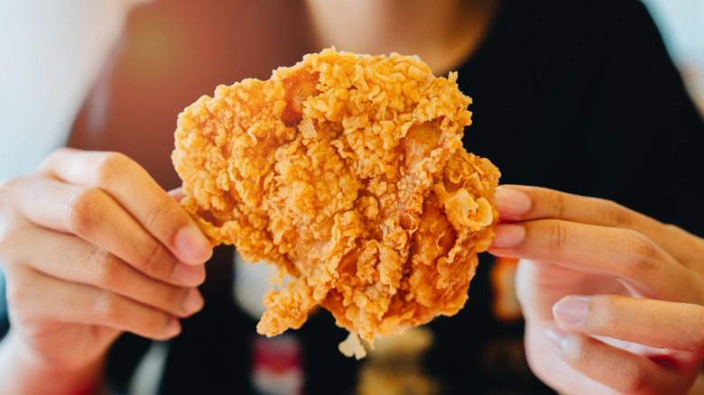 Customer holding up a piece of fried chicken