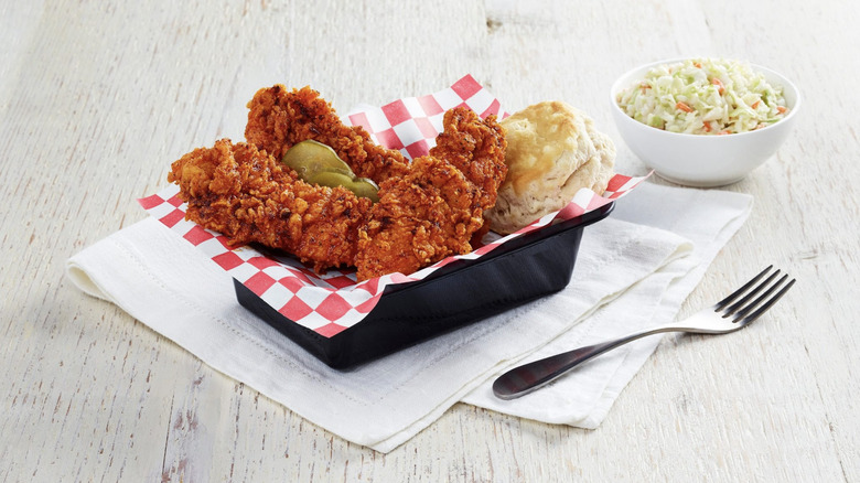 A basket of KFC Nashville Hot Chicken is served with coleslaw and a biscuit.