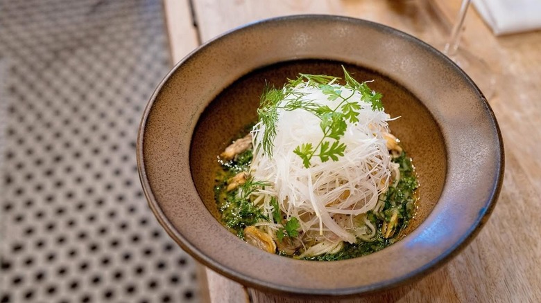 A bowl of noodle soup garnished high with shaved radish from Jeju