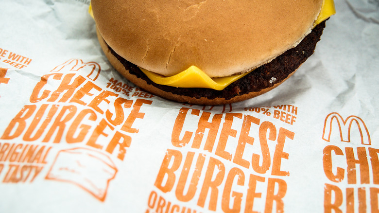 A McDonald's cheeseburger sitting on top a to-go wrapper