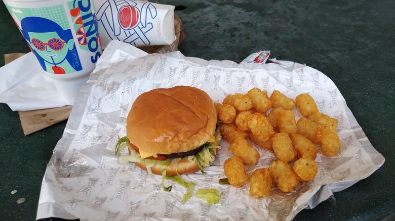 A cheeseburger with tater tots and a drink from Sonic