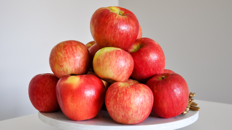 Honeycrisp apples stacked on a white tray.