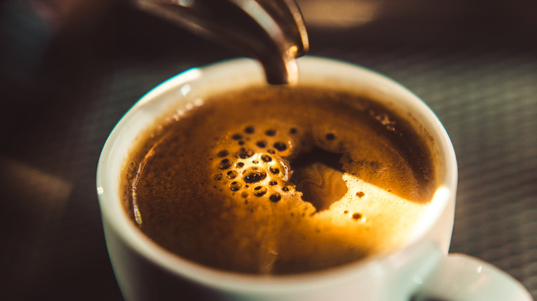 Espresso being poured into a white cup