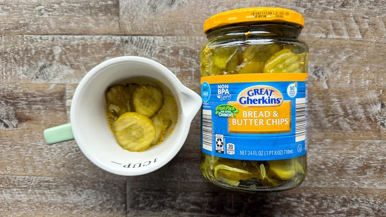 a jar of great gherkins pickles next to a cup