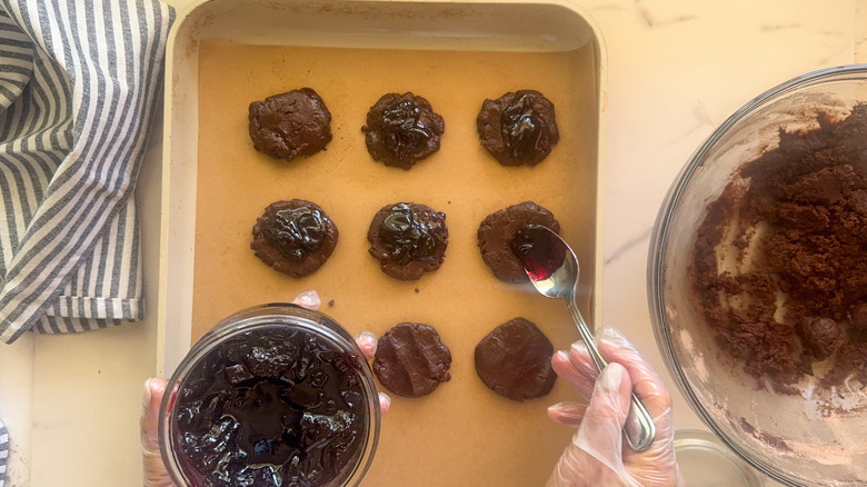 hand adding jam to dough
