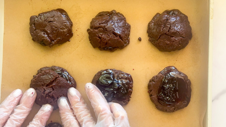 hand adding dough to top