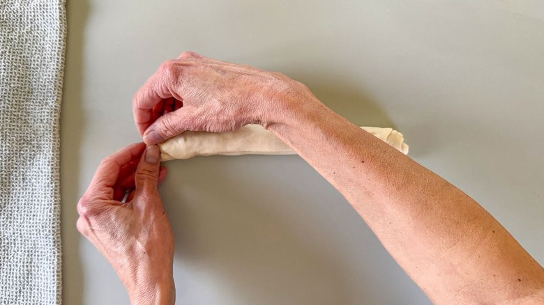 Pinching and sealing the end of rolled up scallion pancake dough