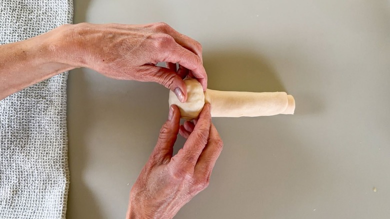 Rolling scallion pancake dough cylinder into a spiral