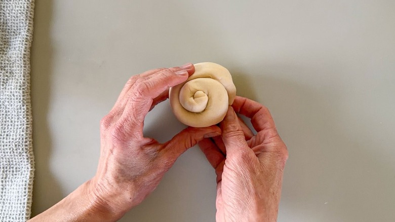 Tucking the end of a scallion pancake spiral roll underneath
