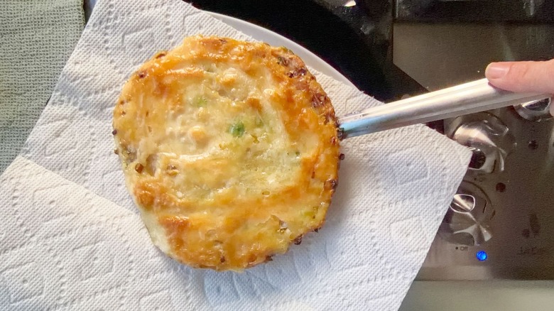 Placing cooked scallion pancake on plate with paper towels
