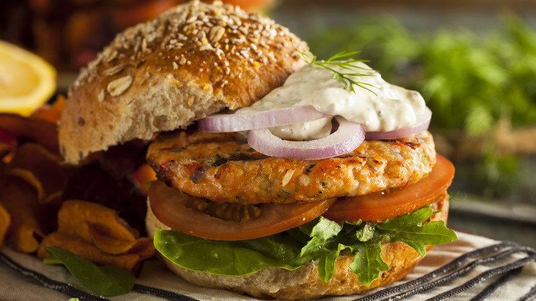 Salmon burger with tartar sauce, tomatoes, and onions