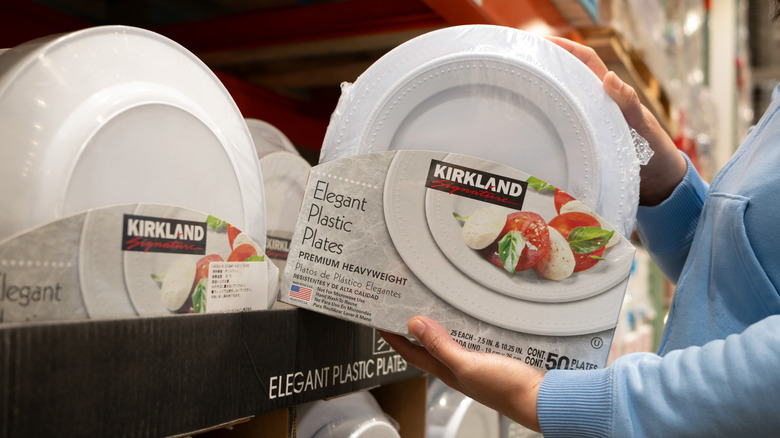Person picking up a set of Costco's Kirkland Elegant Plastic Plates