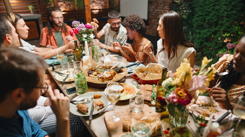 Guests conversing at dinner party table. 