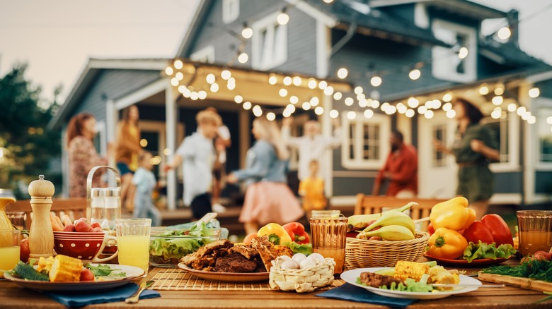 People dancing next to dinner table with food. 