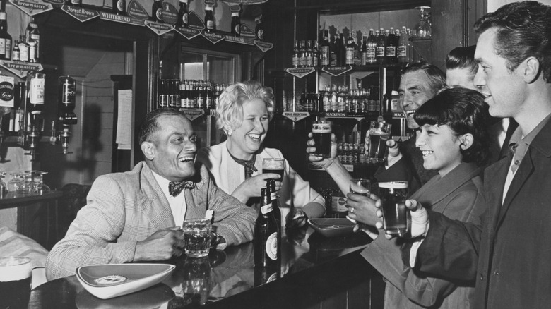 Black & white image of people laughing and drinking beer at a bar