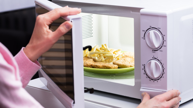 Hands putting food in microwave