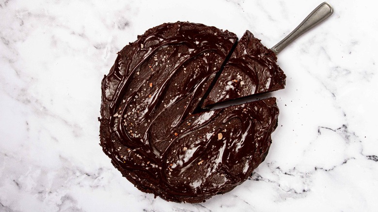 top view of a chocolate cake being served on a marble countertop