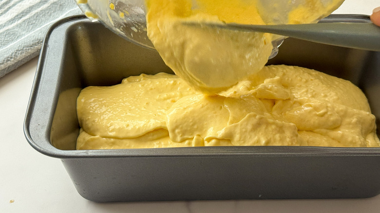 scooping mango ice cream into loaf pan