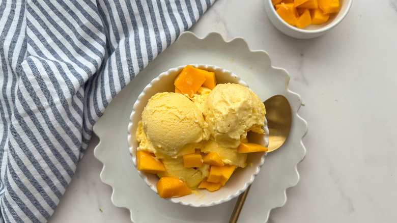 Mango ice cream in bowl with mango chunks on top