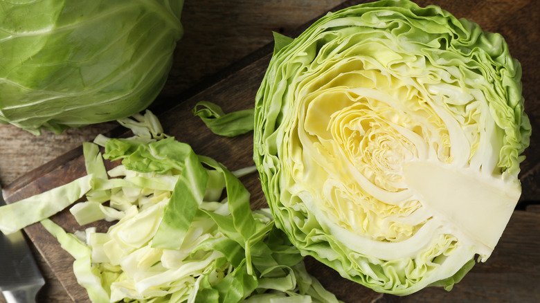 A half head of cabbage with several strips of it beside it