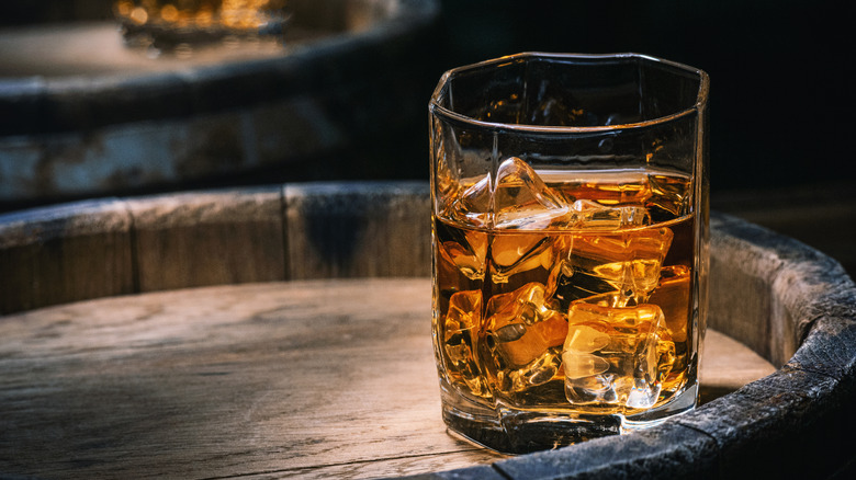 glass of whiskey sitting on a barrel