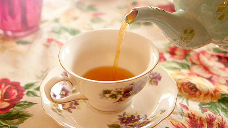 A tea pot pouring a cup of tea