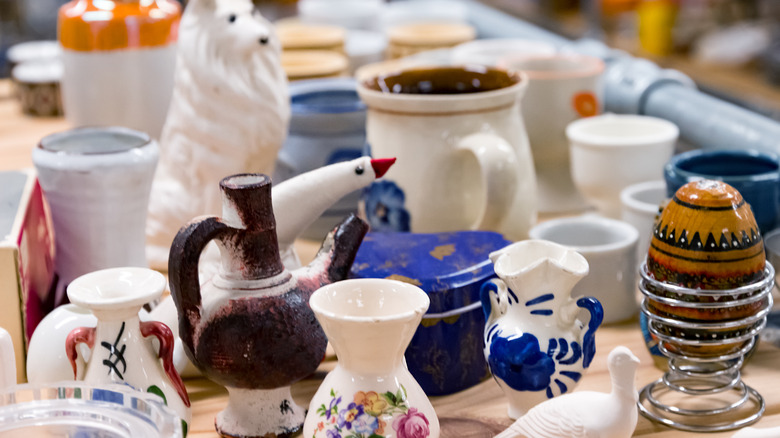 Different kinds of vintage and unique dishware displayed on a wooden table.