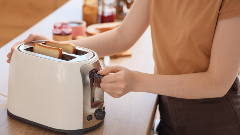 A person toasting two slices of white bread in a toaster.