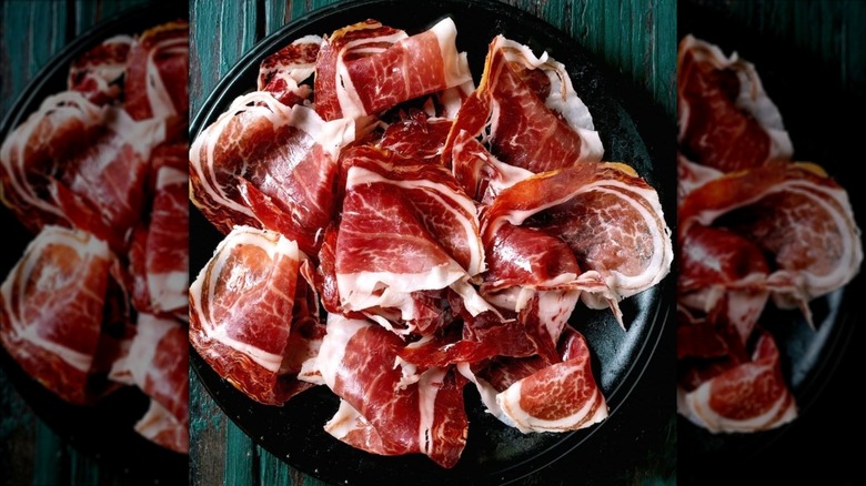 Thin slices of Broadbent's Hillbilly Prosciutto on a black plate from a top-down view
