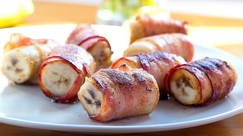 Fully cooked bacon-wrapped banana chunks on a white plate