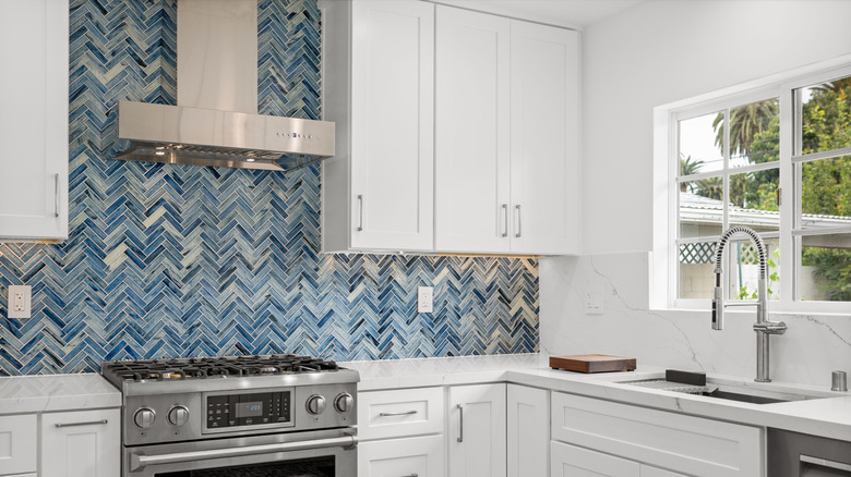 kitchen with blue tiled backsplash and white cabinets
