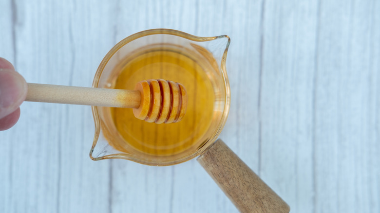 Pouring honey into a measuring cup.