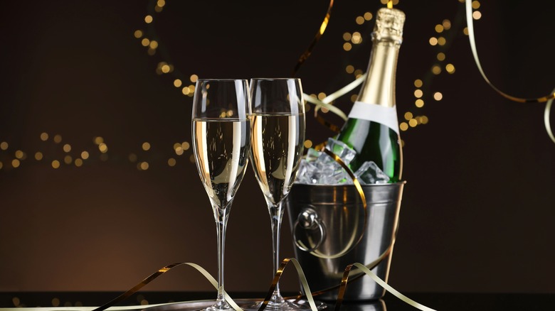 A bucket of champagne on ice and two filled flutes.